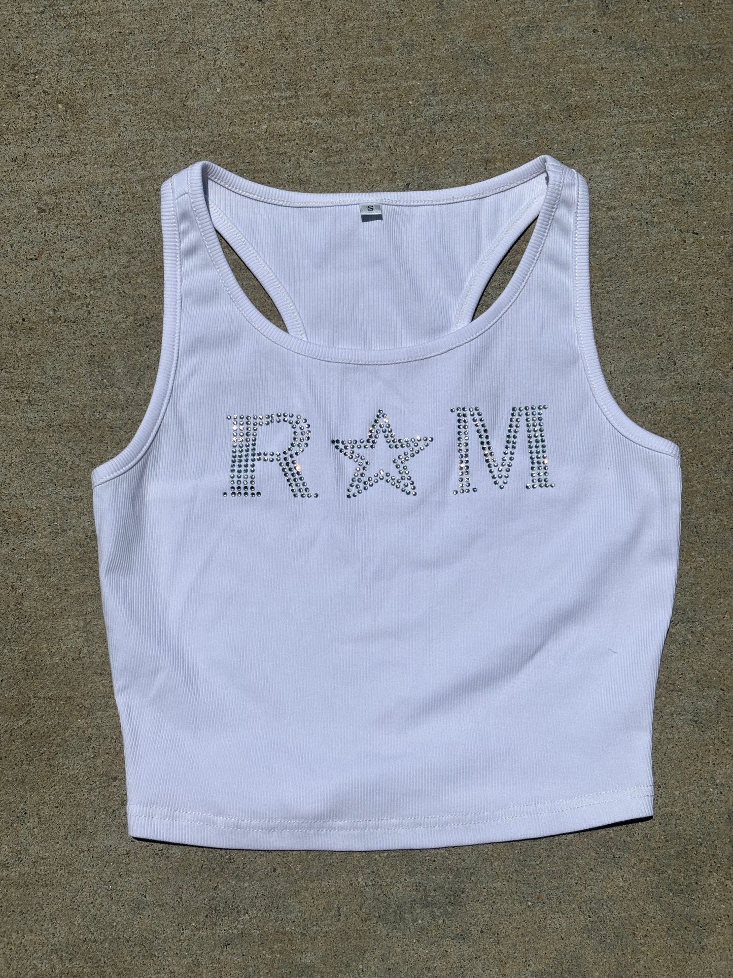 Close-up of a white ribbed crop top with rhinestone "RM" lettering and star worn with jeans – urban glam style by Renegade Mafia