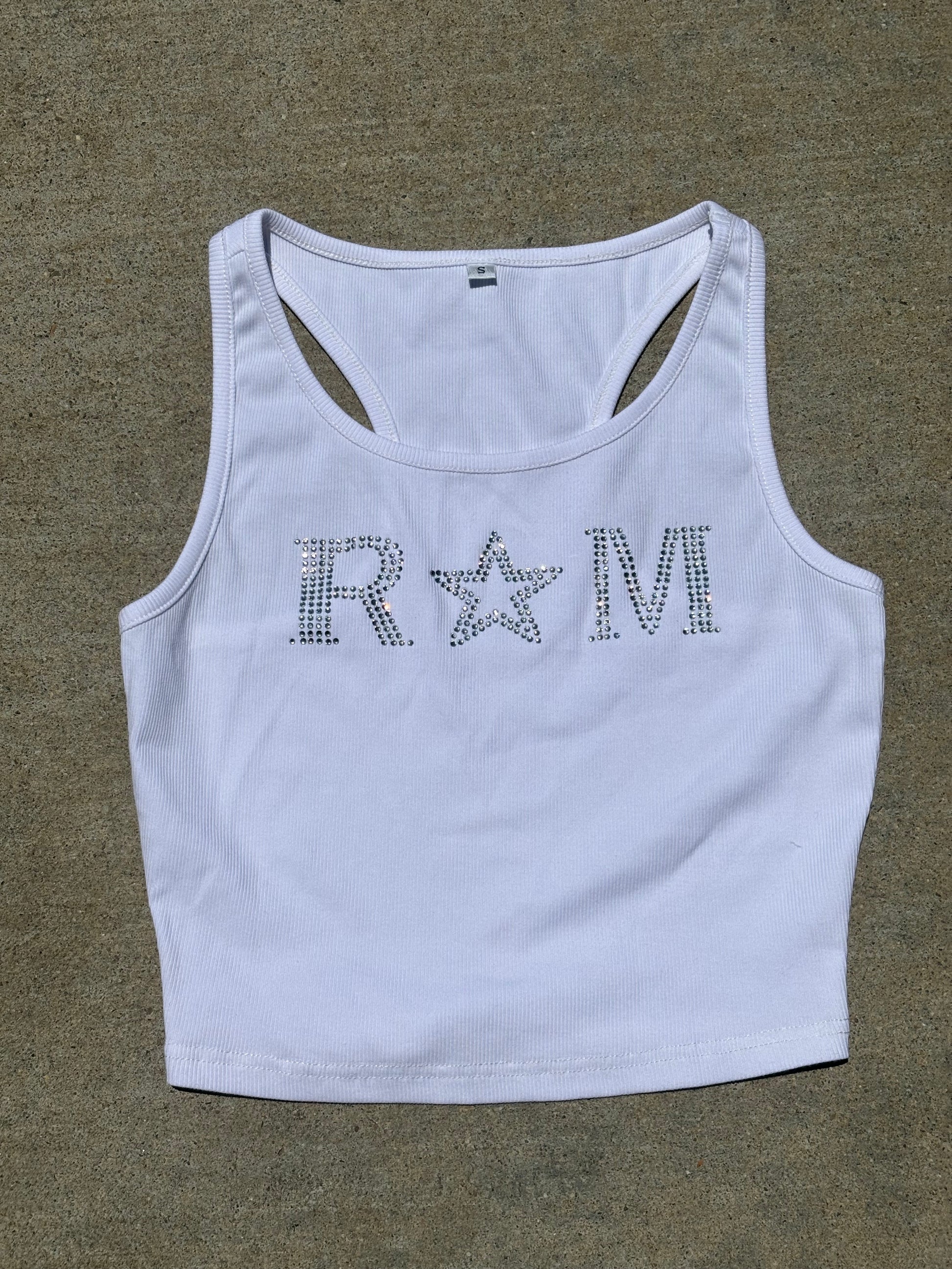 Close-up of a white ribbed crop top with rhinestone "RM" lettering and star worn with jeans – urban glam style by Renegade Mafia