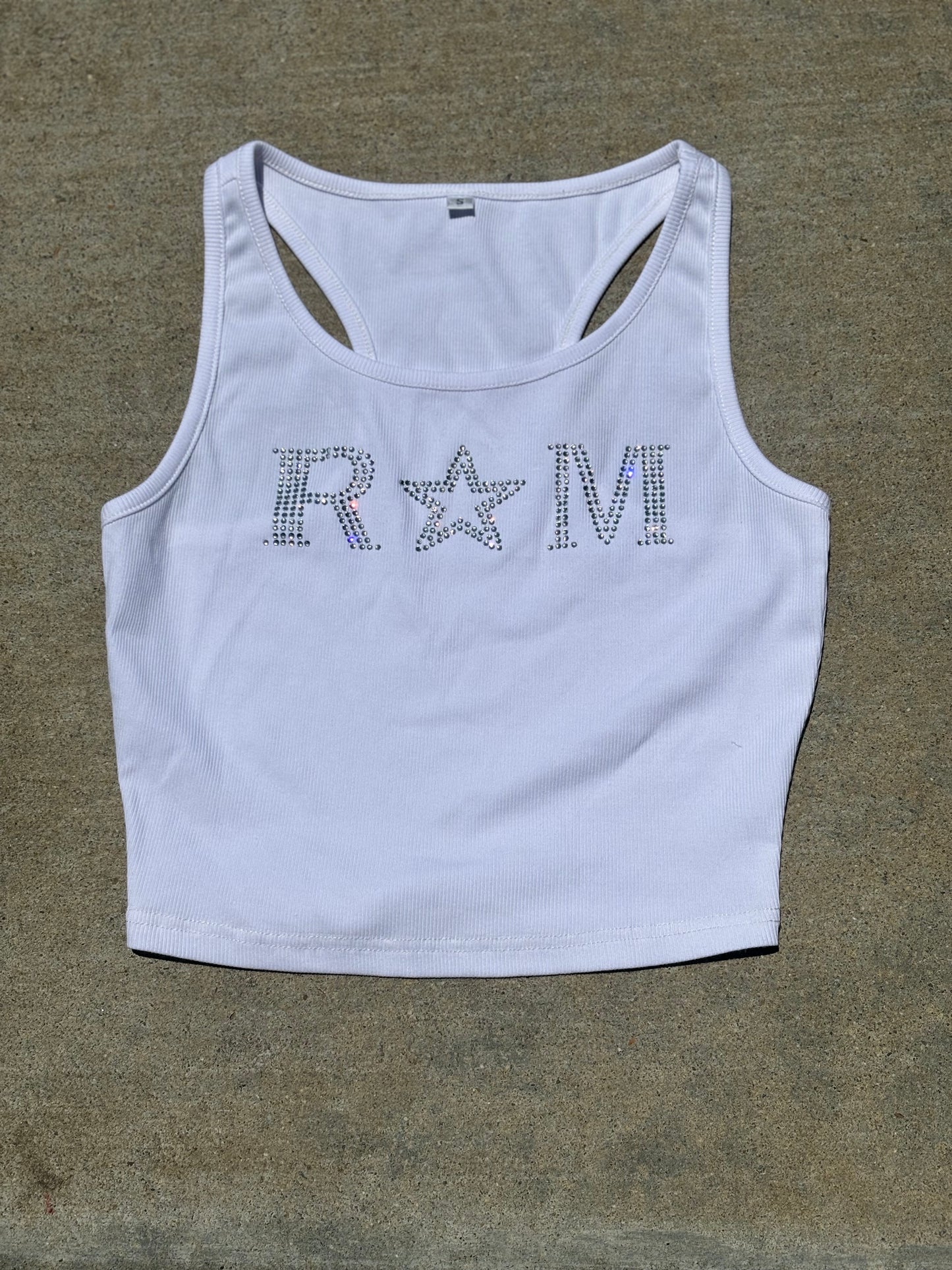 Close-up of a white ribbed crop top with rhinestone "RM" lettering and star worn with jeans – urban glam style by Renegade Mafia