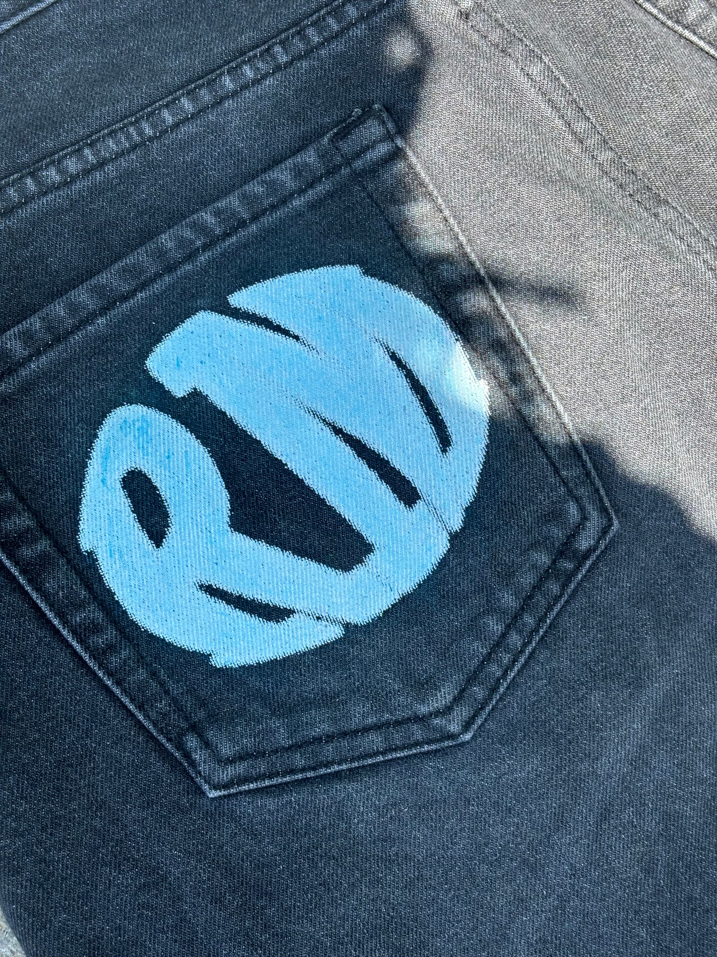 Detailed view of blue RM printed logo on denim back pocket by Renegade Mafia