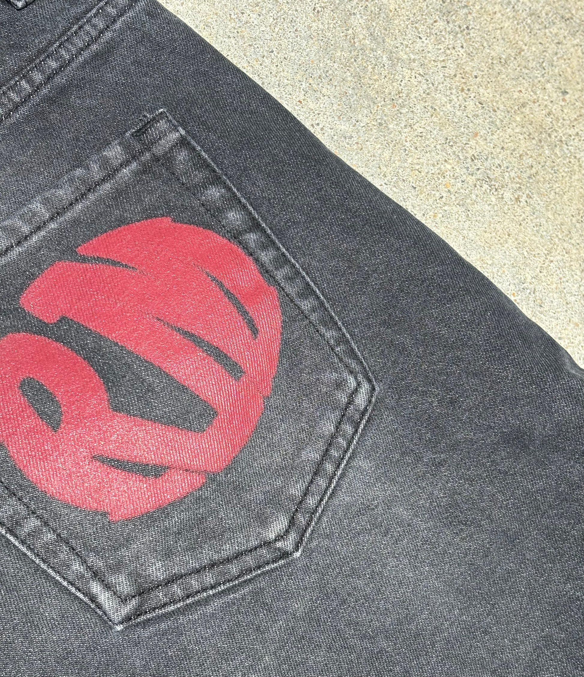 “Detailed view of red RM printed logo on back pocket of Renegade Mafia jeans”